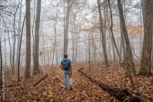 Man person hiker hiking on Cedar Cliffs forest trail in Wintergreen Resort, Virginia standing looking at view in morning fog, foggy weather