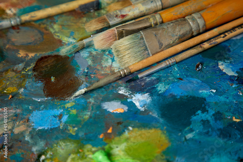 Tubes of oil paint, palette and artist paintbrushes closeup.