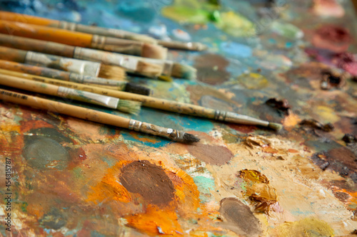 Tubes of oil paint, palette and artist paintbrushes closeup.