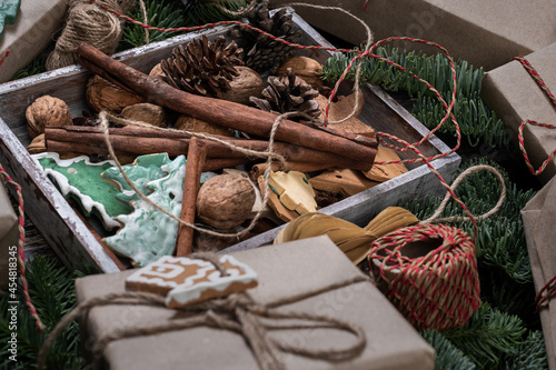 Wrapping rustic eco Christmas packages with brown paper  string and natural fir branches on dark background