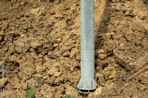 A pillar in the ground. Dug up the ground under the metal pillar. Construction work.