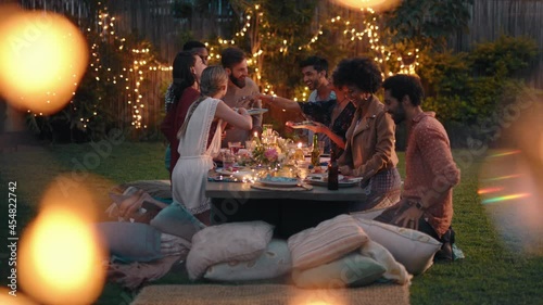 young group of friends celebrating at dinner party chatting sharing healthy food sitting at table enjoying weekend reunion relaxing on beautiful summer evening outdoors 4k