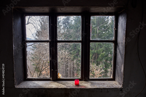 Old glass window with peeling frame and red candle.