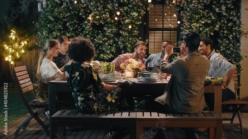 group of friends celebrating evening dinner party sharing homemade meal enjoying casual conversation having fun weekend reunion relaxing on calm summer night outdoors 4k footage