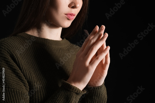 Praying young woman on dark background