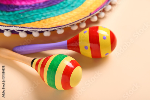 Mexican maracas and sombrero on color background