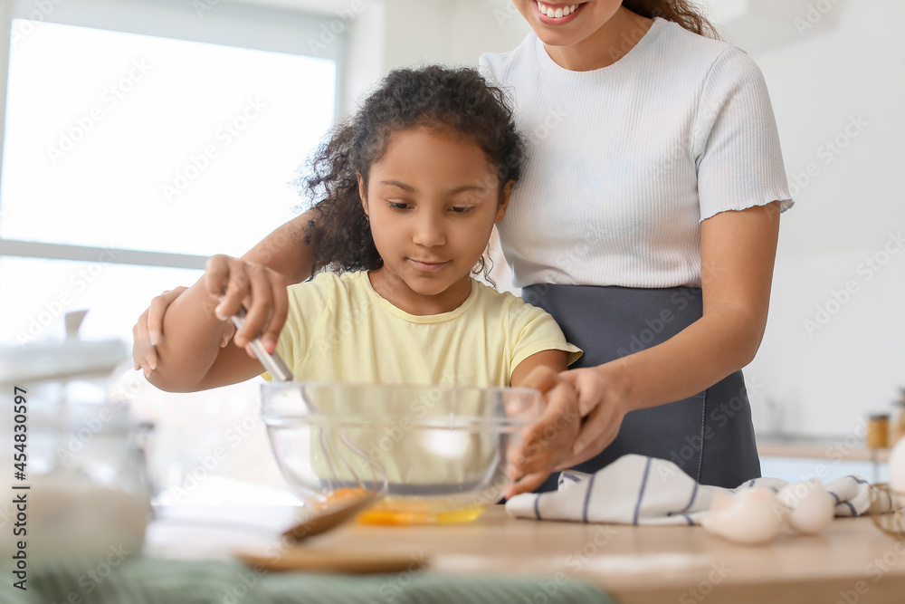 African-American little girl and her mother cooking in kitchen African-American little girl and her mother cooking in kitchen