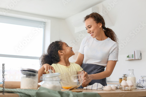 African-American little girl and her mother cooking in kitchen