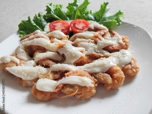 Fried shrimp butter with mayonnaise and Lettuce against a wooden background.