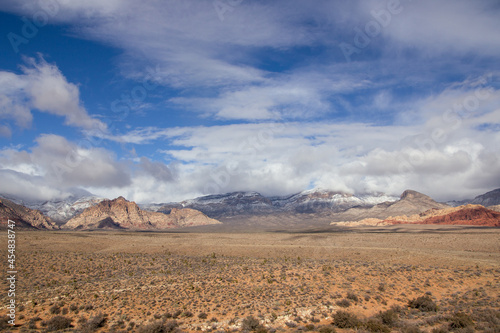 Snow on mountains in desert canyon with dramatic clouds