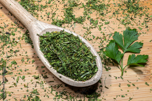 Whole and chopped parsley (Petroselinum crispum) leaves on a wooden background. Photo produced in a studio