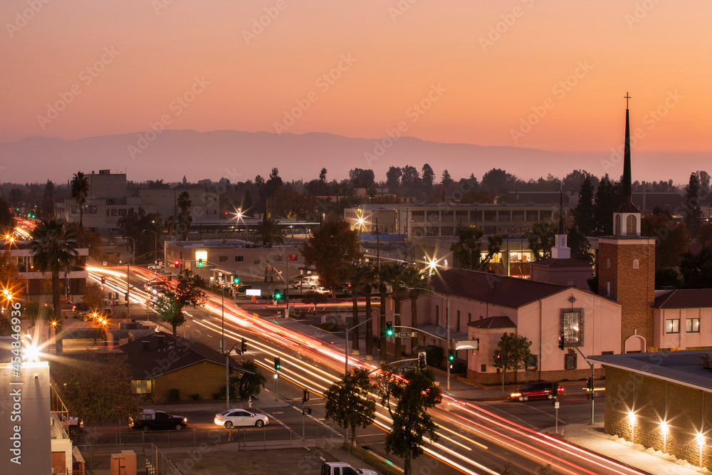 Evening traffic streams through downtown Bakersfield, California, USA, at sunset.