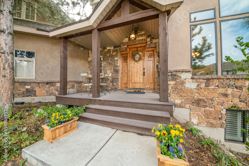 Porch of a house with huge single wooden door with wreath and lockbox © Jason