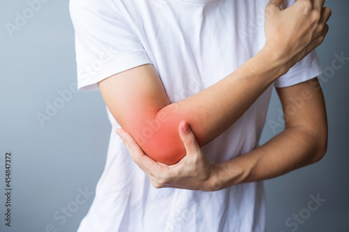 Young adult female with her muscle pain on gray background. Woman having elbow ache due to lateral epicondylitis or tennis elbow. injuries and medical concept photo