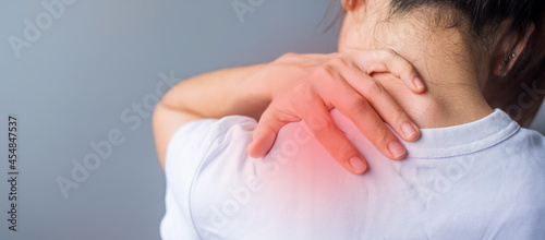 woman with her shoulder sprain, muscle painful during overwork. Girl having body problem after wake up. Shoulder ache, Scapular pain, office syndrome and ergonomic concept photo