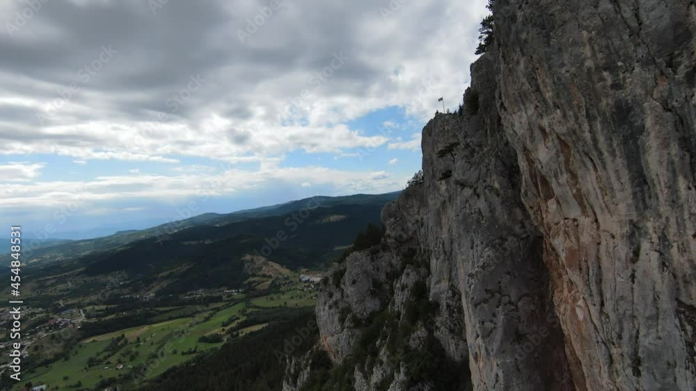 Aerial cinematic shot high speed sport fpv drone flying over natural mountain cliff surrounded Amazing nature rocky terrain with green vegetation and forest on cloudy day. 
