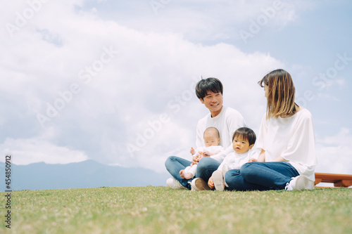 空と芝生に座る家族・ファミリー（4人） 