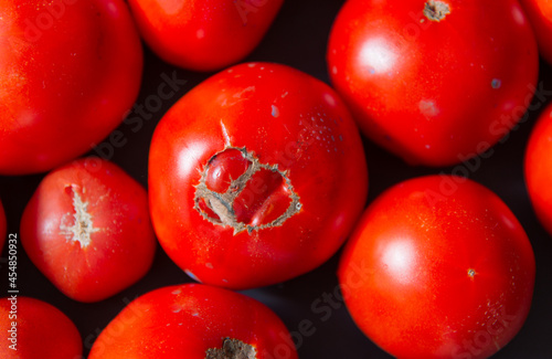 A few tomatoes on a black background, the view from above is large. 