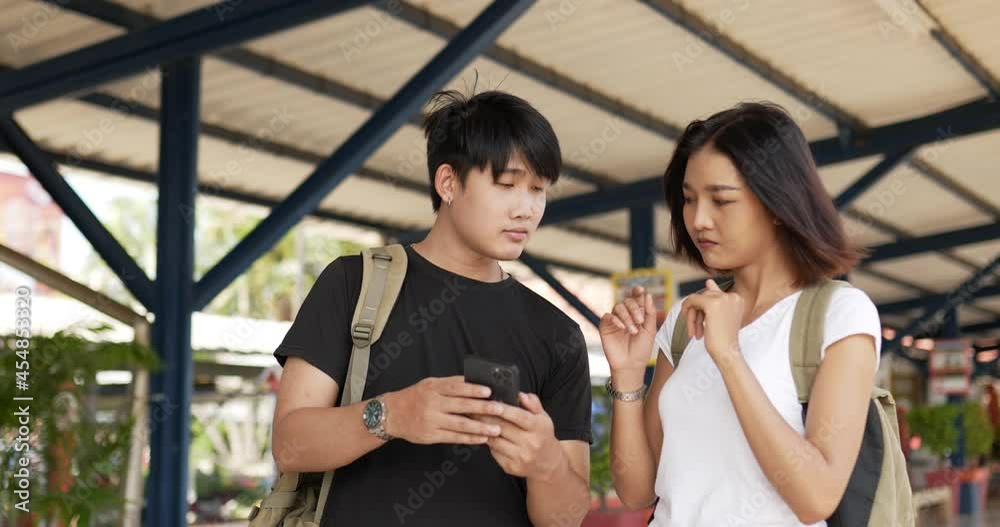 Couple checks location on smartphone online map at train station Couple checks location on smartphone online map at train station