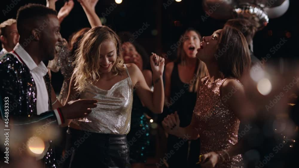 fun party friends celebrating new years eve dancing throwing confetti enjoying glamorous celebration wearing stylish fashion social gathering on rooftop at night 4k 