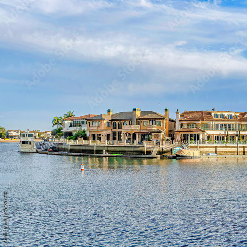 Square Waterfront homes with private docks overlooking the sea under cloudy blue sky