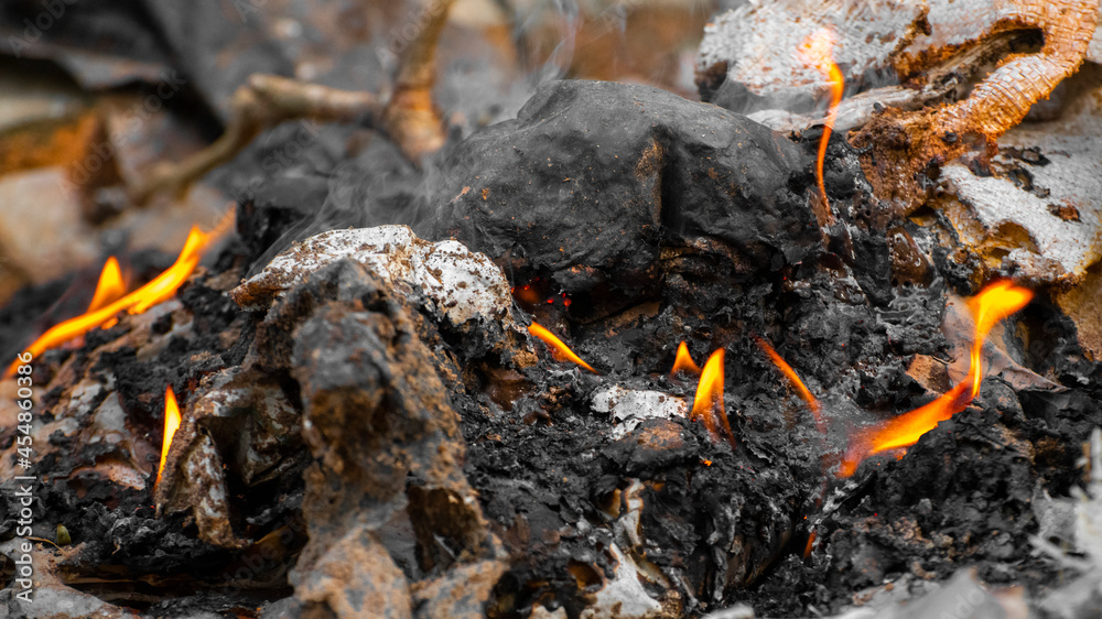 Burning the trash collection outside. Burnt ashes and the sparks of small flames close up. Burning the trash collection outside. Burnt ashes and the sparks of small flames close up.