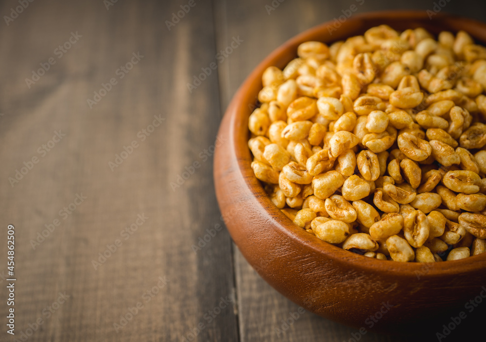 Wheat flakes cereal breakfast in wooden bowl on the rustic background. Selective focus. Wheat flakes cereal breakfast in wooden bowl on the rustic background. Selective focus.
