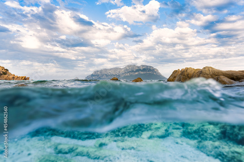 Obraz na płótnie (Selective focus) Split-shot, over-under shot, half in half out. Crystal clear, turquoise water in the foreground and Tavolara Island in the distance. Sardinia, Italy. w salonie