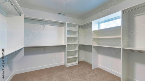 Pano Walk in closet of house with empty built in shelves and two levels clothing rods