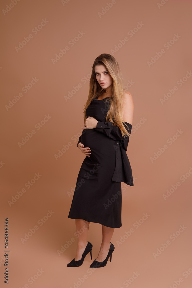 Beautiful pregnant young woman in studio on beige background Beautiful pregnant young woman in studio on beige background