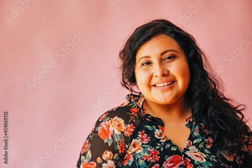 Fotografía Portrait of smiling young woman wearing floral top against pink wall at home