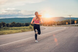 Young woman runner running on city road with mountains in the background.
