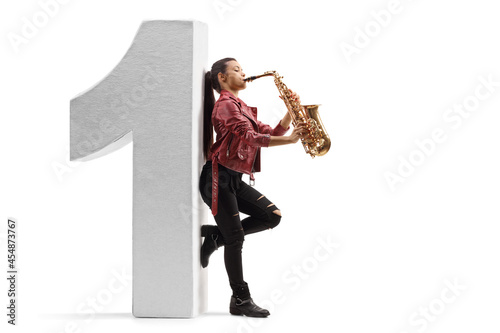 Full length profile shot of a female saxophonist playing and and leaning on a number one photo