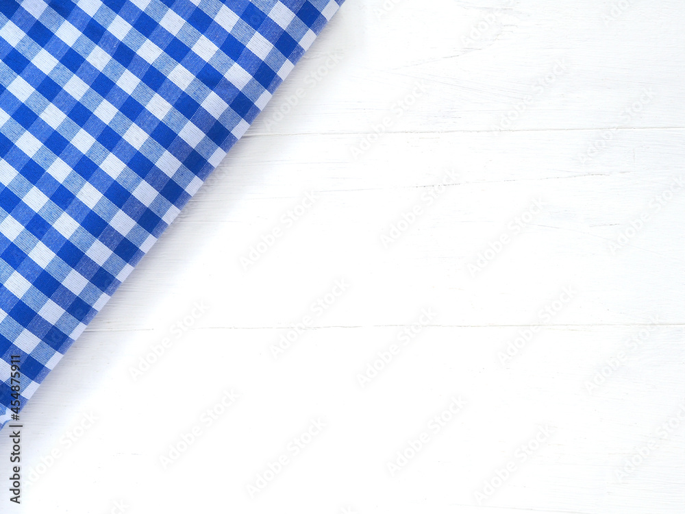 Top view, close-up of blue and white checkered fabric or napkin on white table background. Concept kitchen utensils and tableware. Top view, flat lay with copy space.. Top view, close-up of blue and white checkered fabric or napkin on white table background. Concept kitchen utensils and tableware. Top view, flat lay with copy space..