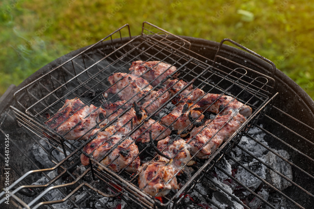 Seasoned pork on the grill. Grilling shashlik outside on a barbecue grill. Outdoor grill party in the summer season. Sunny summer evening.