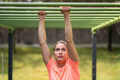 Strong blonde woman in an outdoor gym doing exercise
