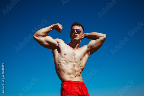 Portrait of a handsome muscle young man with stylish haircut. Perfect body. Close up. Outdoor shot
