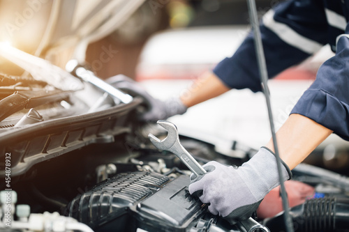 Mechanic works on the engine of the car in the garage. Repair service. Concept of car inspection service and car repair service.