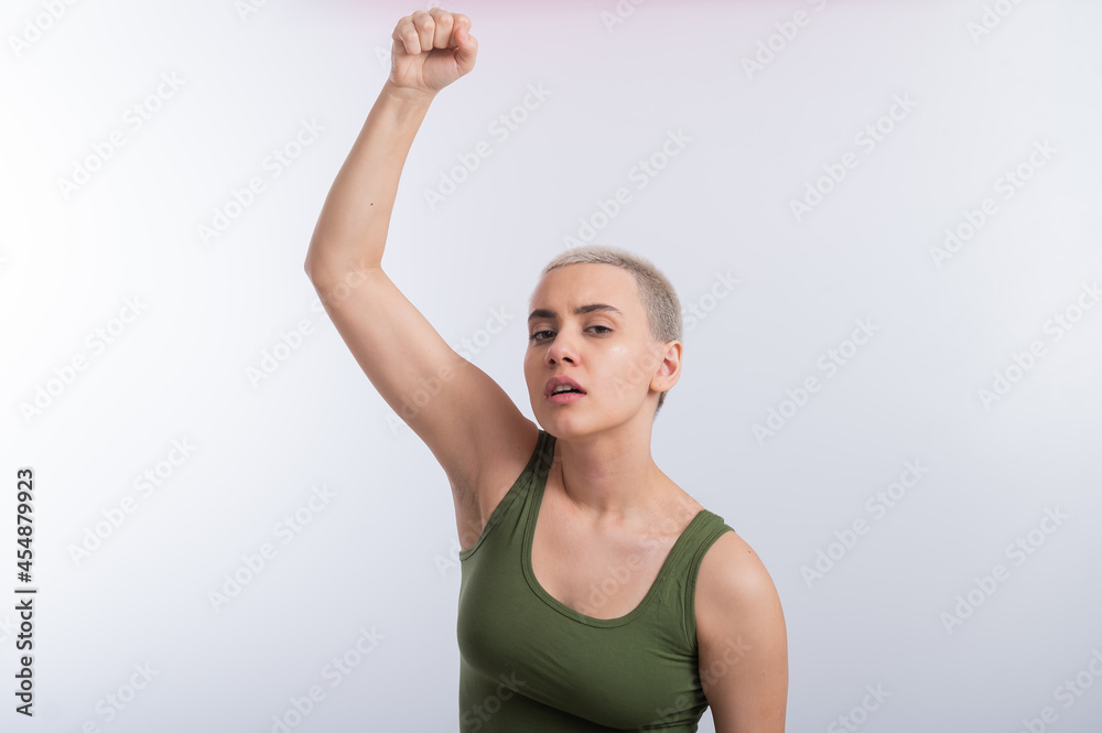 Young caucasian woman holding her fist up on a white background. A girl with short hair is fighting for rights Young caucasian woman holding her fist up on a white background. A girl with short hair is fighting for rights