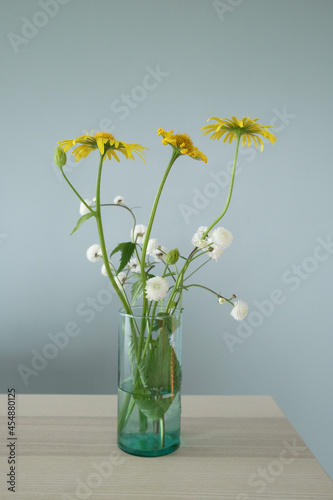 Yellow and white flowers in a vase on a table.