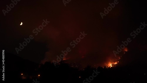 Pisa, Italy. Forest fire at night. Composition with moon in the top left