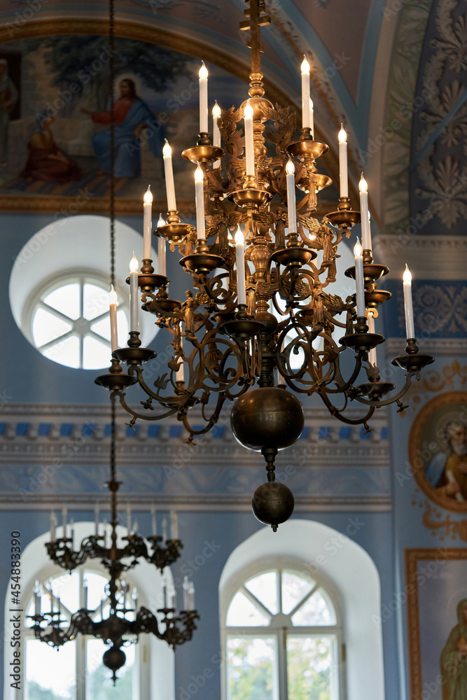 A large chandelier with candles hangs from the ceiling in the church