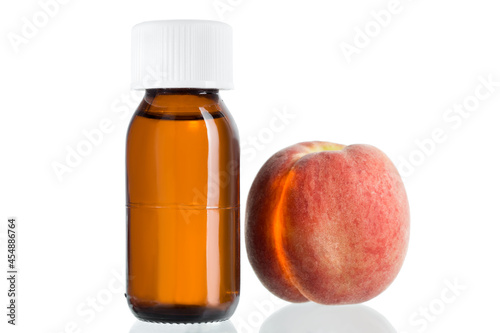 Peach oil in glass bottle with cap and fresh peach fruit isolated on white background, nobody.