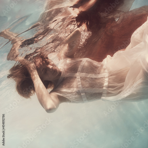 Girl in a white dress and with a red cloth emotional portrait underwater