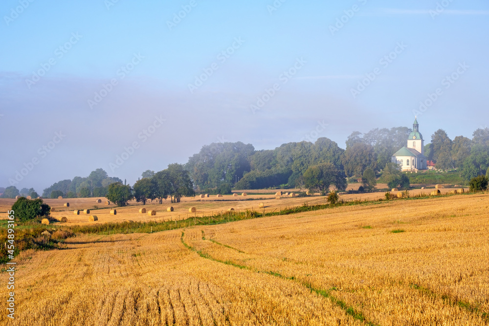 Rural landscape stubble field and a  white country church
