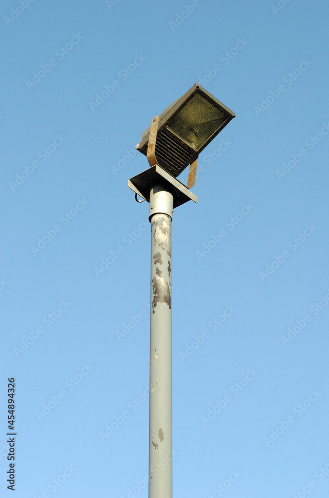 Isolated Floodlight on High Steel Pole against Blue Sky Isolated Floodlight on High Steel Pole against Blue Sky