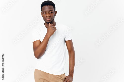 handsome man african appearance in white t-shirt pensive look light background