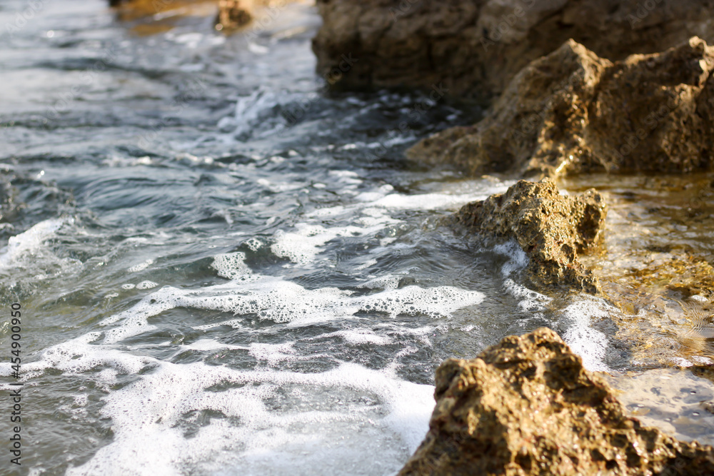 Stone in sea with wave on sunset