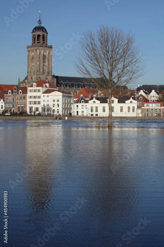 The facades of beautiful old buildings and the tower of the Great Church in the city of Deventer  The Netherlands  with reflection in the river IJssel