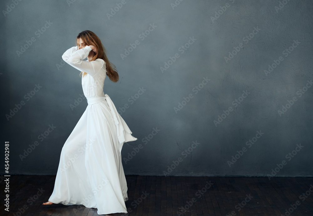 woman barefoot in a white dress dancing on a dark background